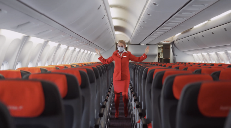 Austrian Airlines hostess che indica le uscite ballando, screenshot da youtube https://www.youtube.com/watch?v=vH-zGql7Y_A&t=12s